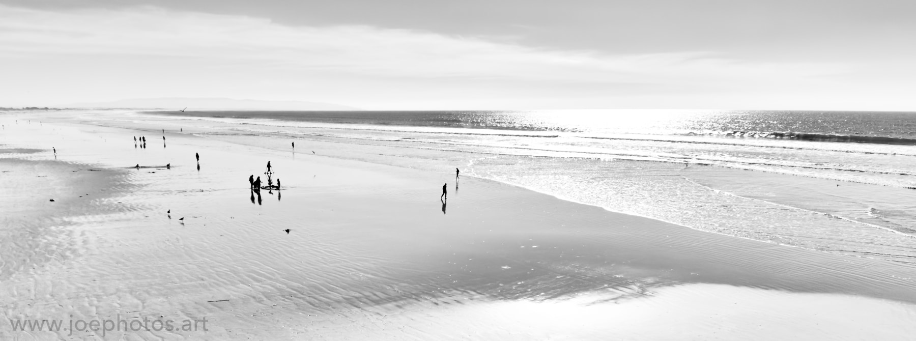Monochrome people on a bright midday beach.
