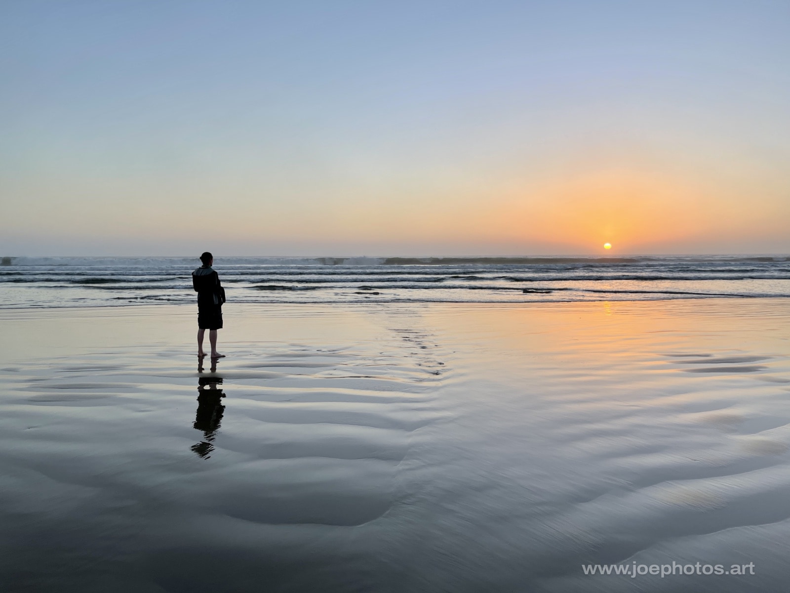 Man at reflective ocean sunset.