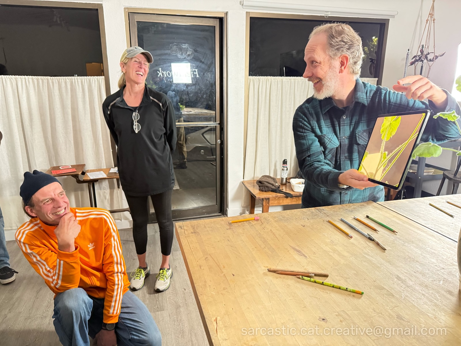 Joe holds an iPad to demonstrate composition and lighting to several other people.